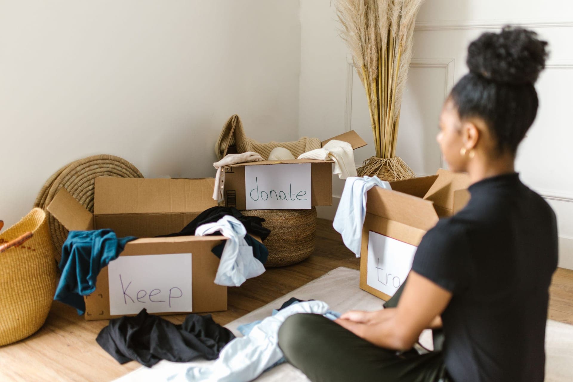 Beim Entrümpeln wird Kleidung in Kartons zum Behalten und Spenden sortiert
