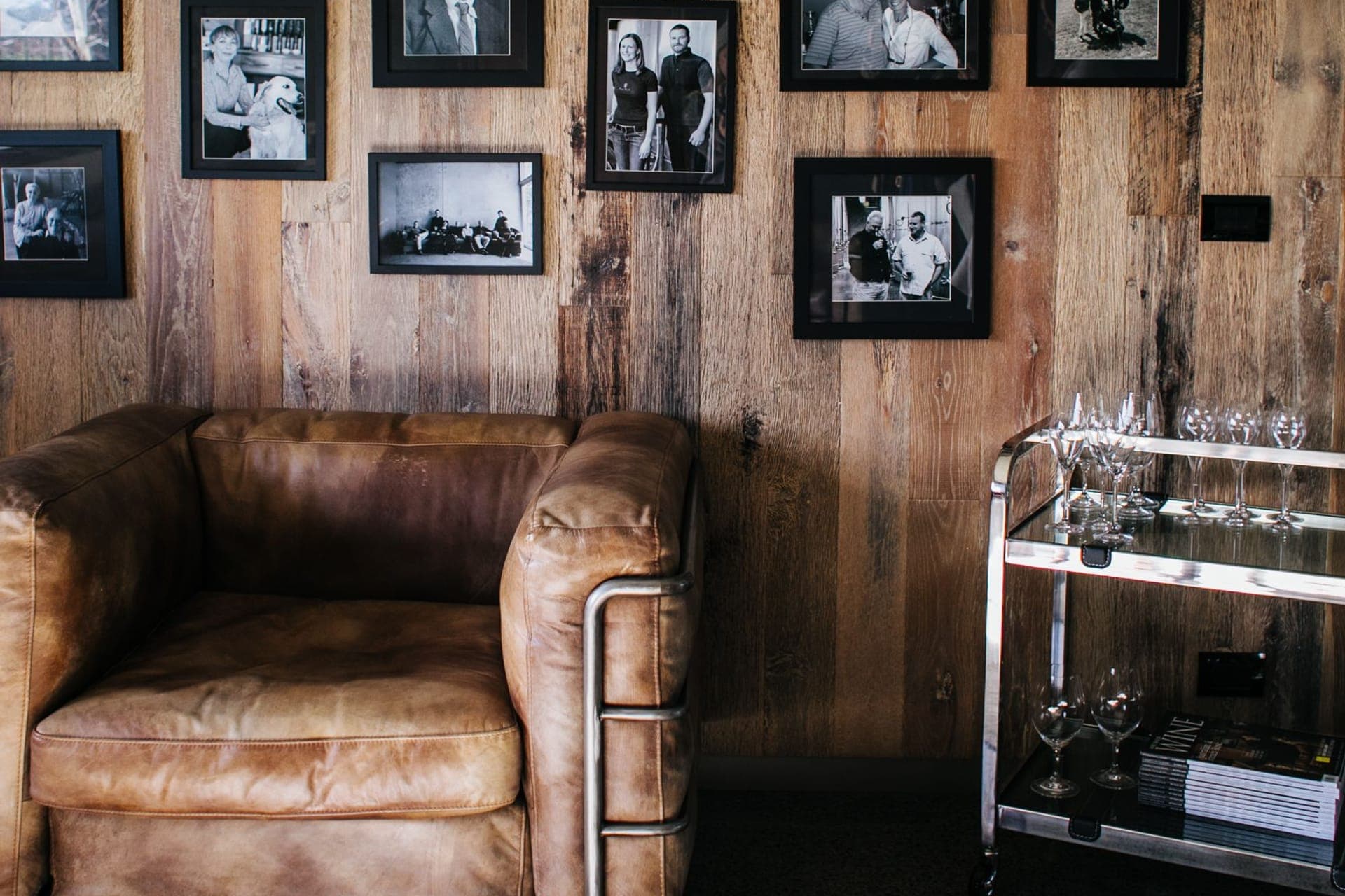 Wohnzimmer mit Ledersessel und gerahmten Familienfotos an der Holzwand